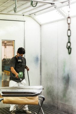 Sprey kabin boyacısı arabanın kapısını yeni boya katmanıyla boyuyor.