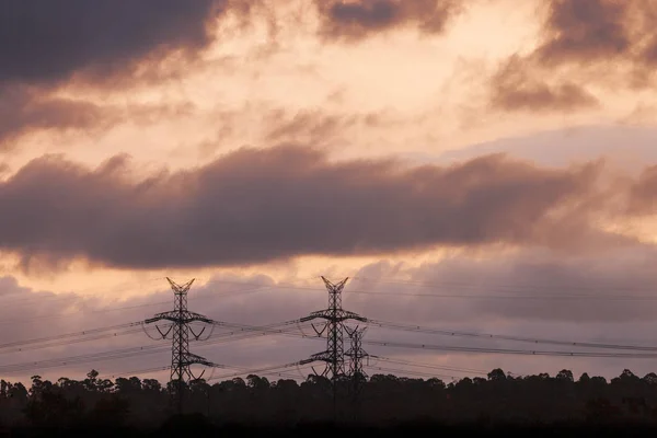 Strommasten stehen in Silhouette hinter Sonnenuntergang — Stockfoto