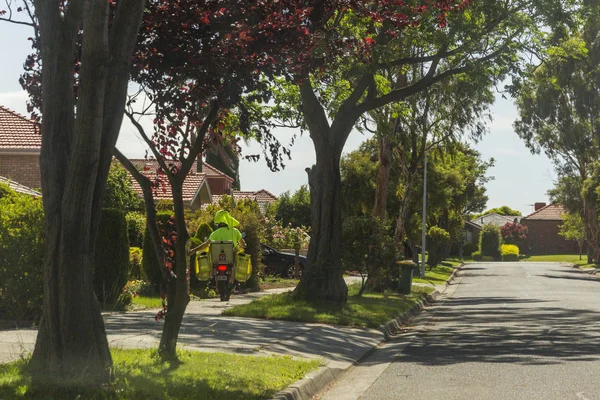 Postino in moto consegna posta su Australian Suburban Street — Foto Stock