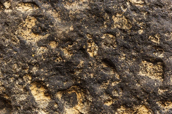 Жовта та чорна вулканічна поверхня приморського скелі — стокове фото