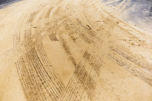 Marcas de neumáticos de construcción grabadas en arena colocada sobre asfalto — Foto de Stock