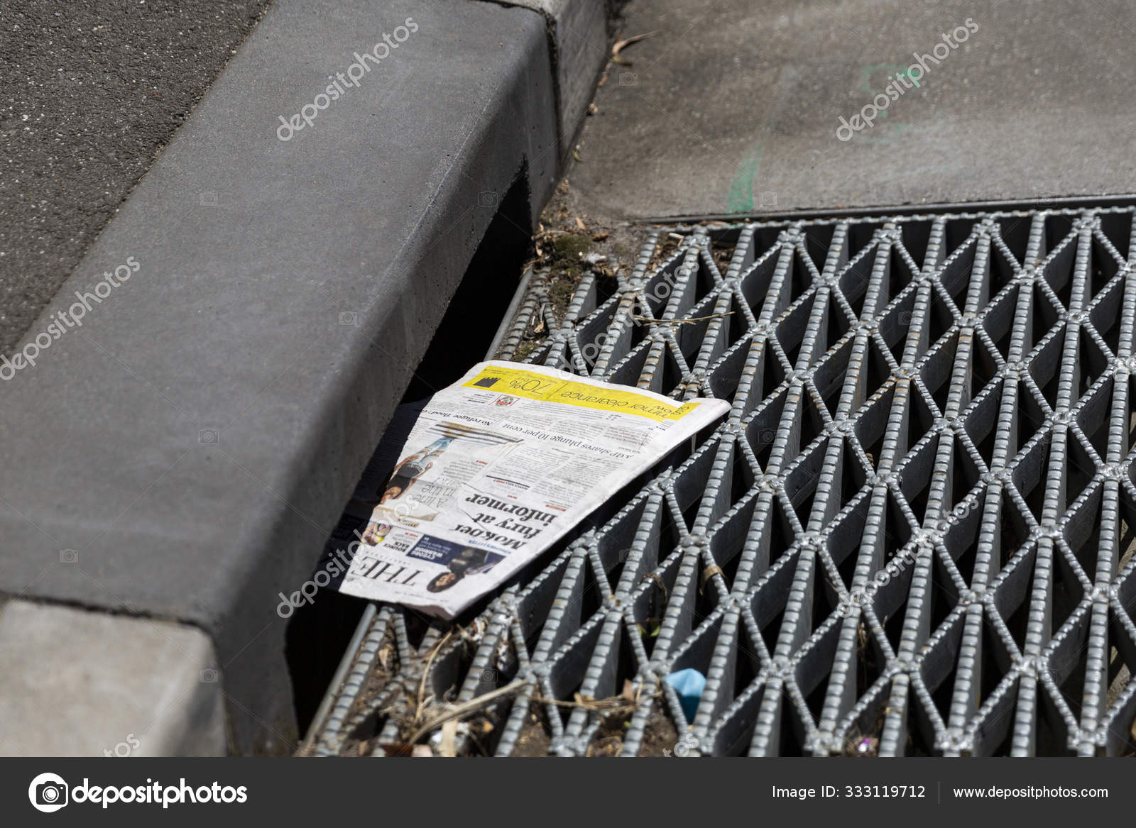 Newspaper Swept Into The Gutter Down A City Drain Stock Photo by ©info