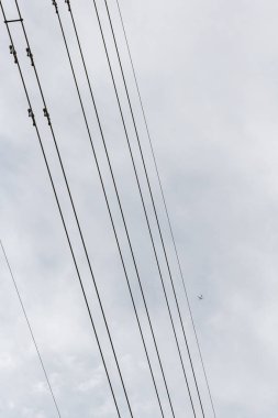 Bulutlu bir günde güç pilonlarının üstündeki Cessna düzlemi