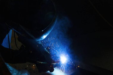 Metal işçileri, gözleri parlak kaynak kirişinden korur.