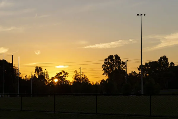 Pôr-do-sol da tarde sobre campo desportivo silhueta abaixo — Fotografia de Stock