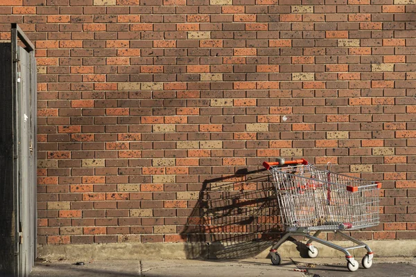 Abandoned Shopping Cart Left Behind Against Red Brick Wall — 스톡 사진
