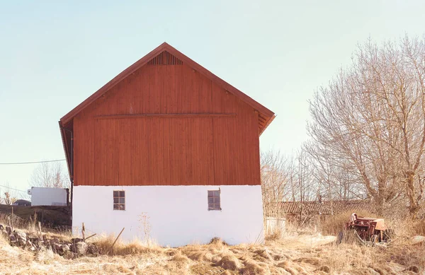 Röd bondgård med två fönster under vårvintern — Stockfoto