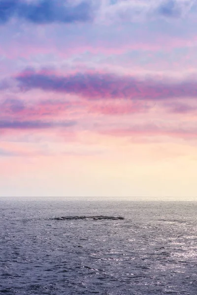 Parzialmente nuvoloso a un tramonto colorato in riva al mare con piccoli isolotti — Foto Stock