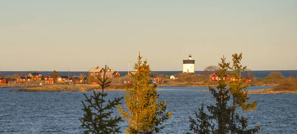 Lighthouse at panoramic sunset in Sweden with small classic red buildings during sunset — Stock Photo, Image