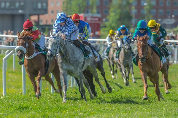 Horses with jockeys out of a curve in fast pace at Nationaldagsg — Stock Photo, Image