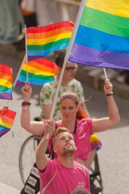 Waving rainbow flag at the pride parade in Stockholm with happy 