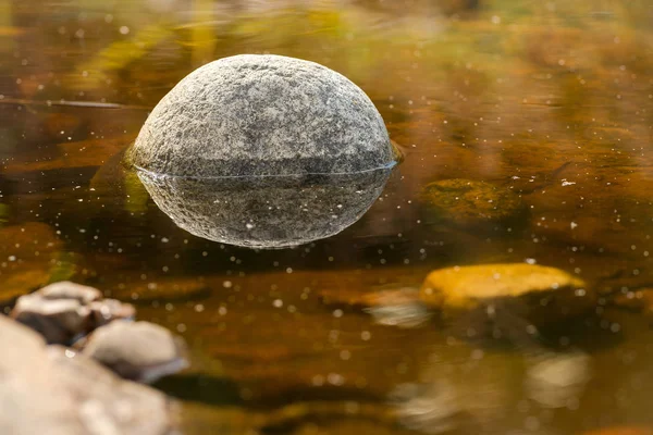 Piedra reflejada en un estanque haciendo una forma de bola —  Fotos de Stock