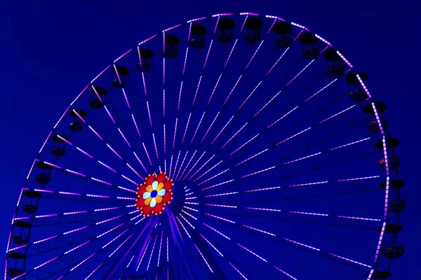 Colorido ferriswheel en colores vivos de neón durante la noche con un — Foto de Stock