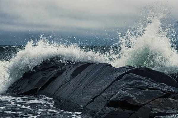 Onde che si infrangono sulla riva delle rocce nere — Foto Stock