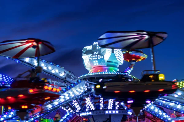 Passeio colorido em um parque de diversões durante a noite com borrão de movimento — Fotografia de Stock