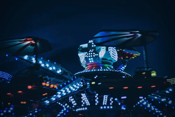 Passeio colorido em um parque de diversões durante a noite com borrão de movimento — Fotografia de Stock