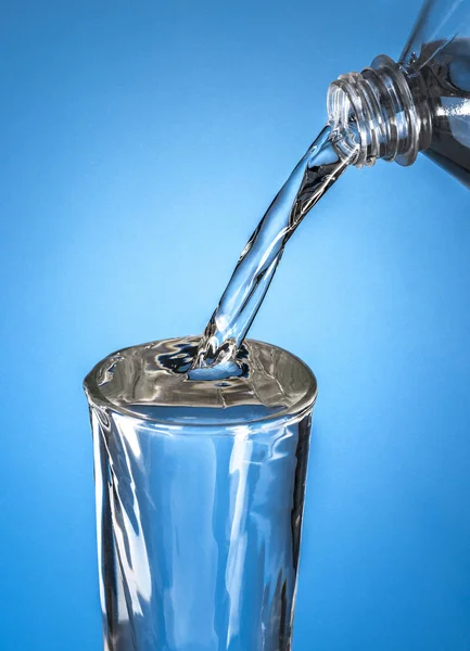 Láhev vody a ve skle — Stock fotografie