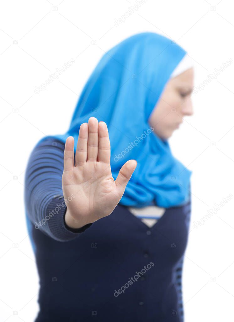 Close up portrait of a serious young muslim woman showing stop refusal gesture with her palm isolated over white background