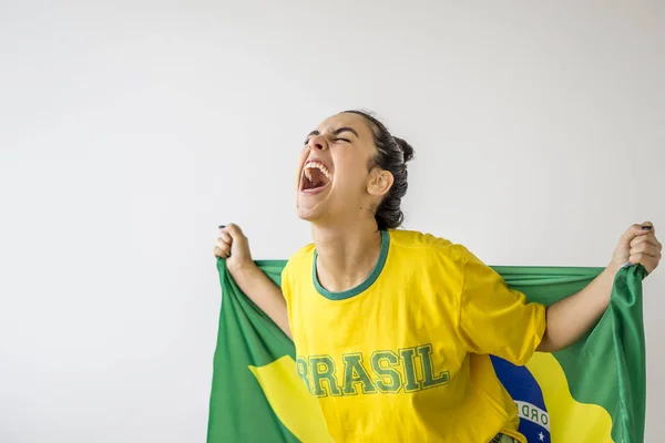 Brazilian fan in yellow t-shirt with brazilian flag on her back on white background