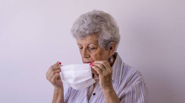 Corona virüsüne karşı koruyucu maske takan yaşlı bir kadın.