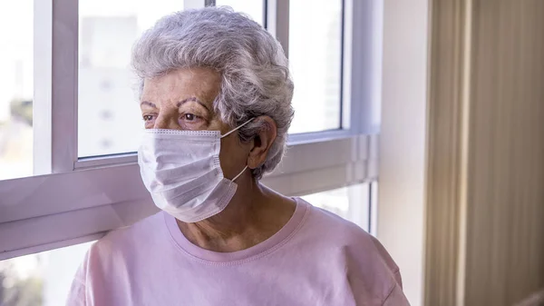 Corona virüsüne karşı koruyucu maske takan yaşlı kadın.