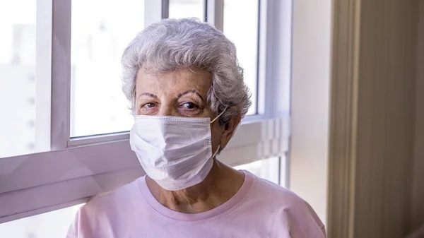 Corona virüsüne karşı koruyucu maske takan yaşlı kadın.