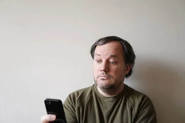 Mann mit großen Augen blickt auf Smartphone — Stockfoto