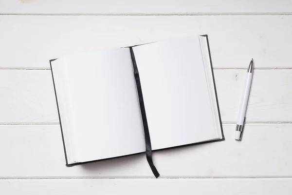 ノートブックを開くと白の木製机の上のペン — ストック写真