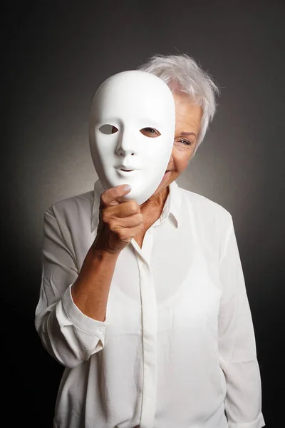 Mulher madura feliz espreitando por trás da máscara — Fotografia de Stock