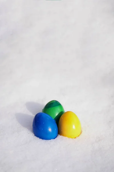 Три пасхальных яйца, окрашенные в яркие цвета в свежий снег — стоковое фото