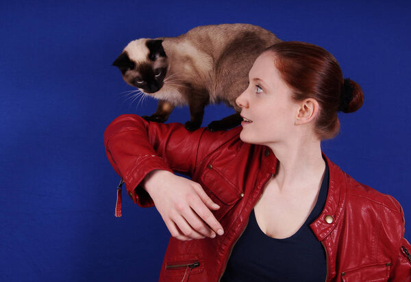 young woman playing with cat on her arm