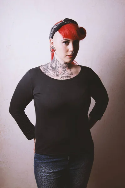 Edgy portret van een jonge vrouw met vele gezichts-piercings en tatoeages — Stockfoto