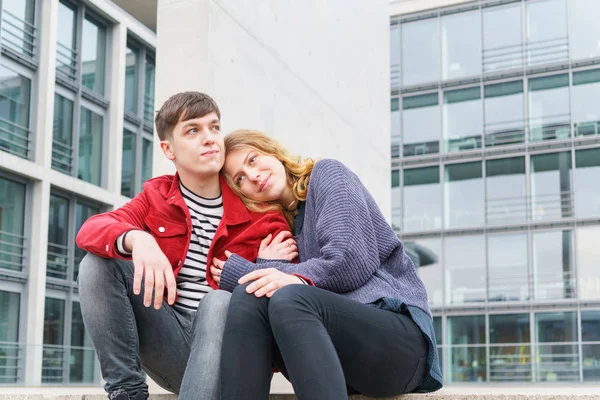 Pareja joven sentada en los escalones frente al edificio moderno — Foto de Stock