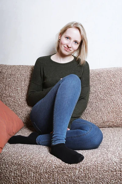 Ung kvinna sitter på soffan hemma — Stockfoto