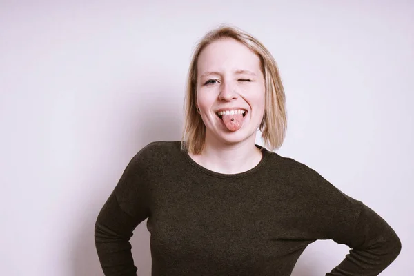 Dumme junge Frau streckt die Zunge heraus und zwinkert — Stockfoto