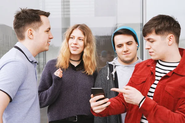 若い男が彼のスマート フォンで何かを見せながら会話 10 代の友人のグループ — ストック写真