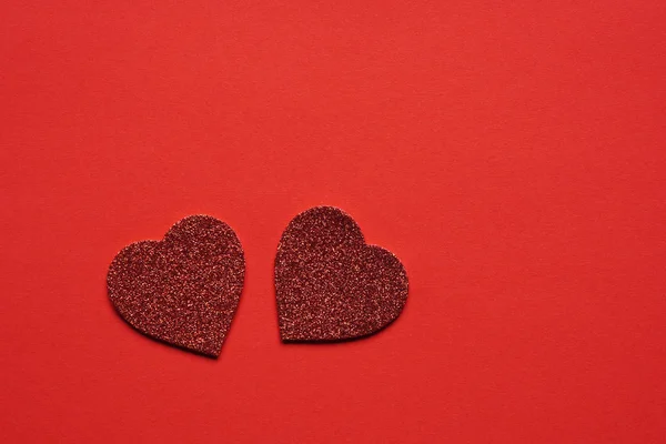 Dos corazones de purpurina sobre fondo rojo — Foto de Stock