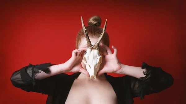 Mysterious occult woman holding animal deer skull in front of her face — Stockfoto