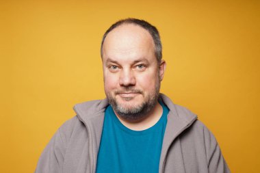 casual chubby mature man against yellow background