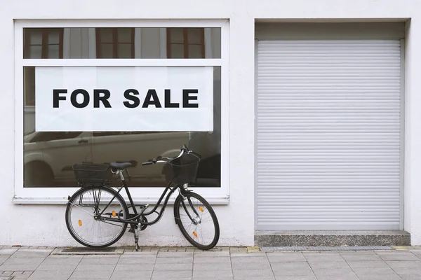 Verkaufsschild im Schaufenster mit Fahrrad, das draußen geparkt ist - Ladenleerstand — Stockfoto