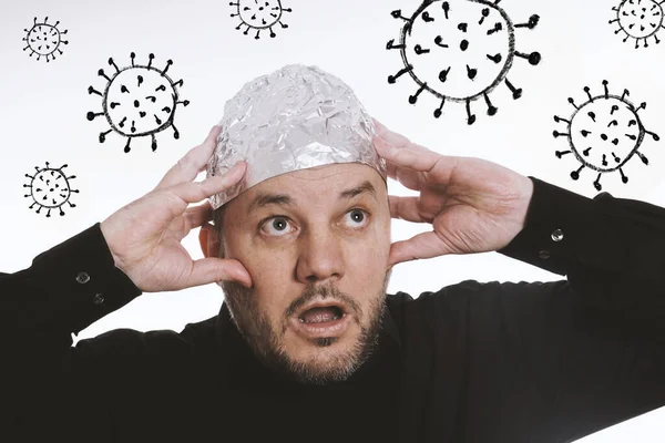 paranoid man wearing tin foil hat against corona virus covid-19