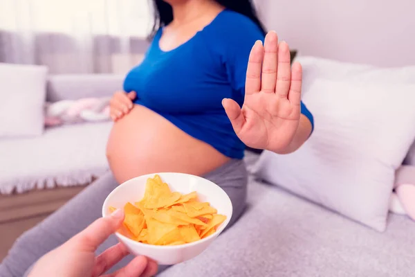 Hamilelik sırasında abur cubur yemeyi bırak. Hamile kadın sağlıksız cips yemeyi reddediyor..  