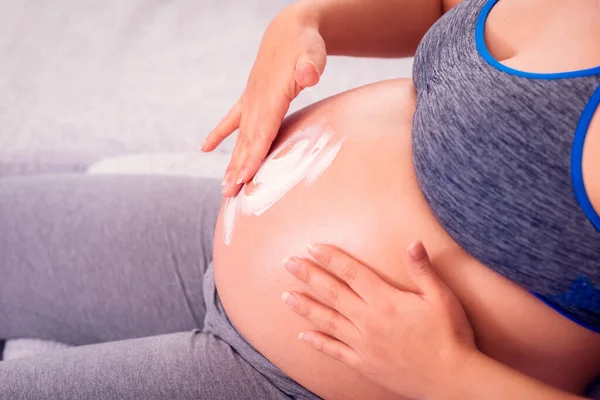 Mujer Embarazada Frotando Vientre Con Loción Corporal Contra Las Estrías Imagen de archivo