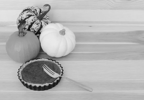 Three pumpkins with small pumpkin pie and fork — Stock Photo, Image