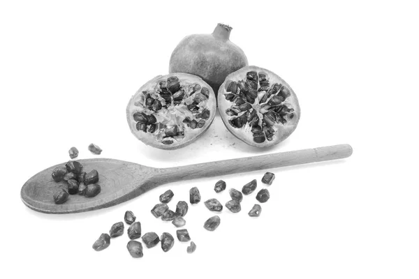 Granatapfel und zwei geschnittene Hälften mit Kernen, die mit einem Löffel entfernt werden — Stockfoto