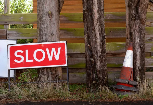 SLOW traffic sign with broken orange and white traffic cones — ストック写真