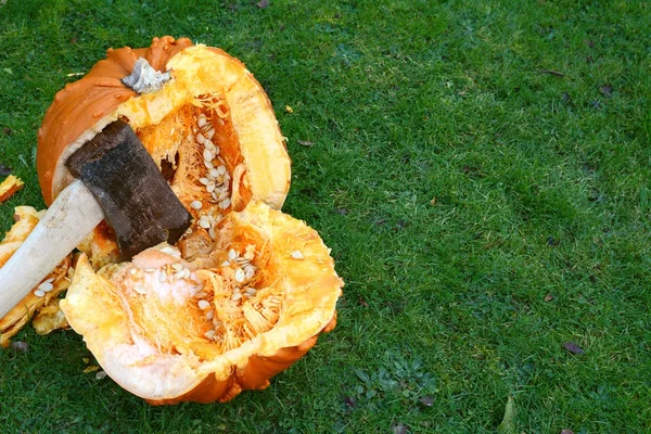 Bijl hacks een grote oranje pompoen doormidden — Stockfoto