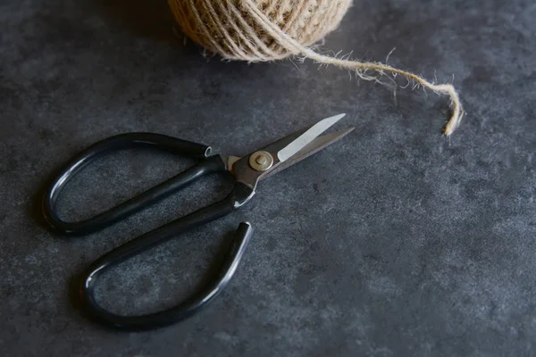 Scissors with rough twine on a grey tile background — Stock Photo, Image