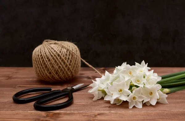 Ball of twine with scissors and white narcissi blooms — Stock Photo, Image