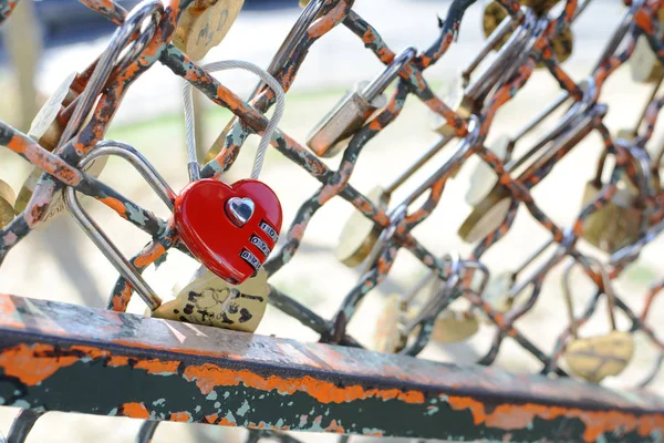 Röd hjärtformad kombination hänglås fäst vid metallstängsel — Stockfoto